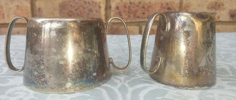A VINTAGE SET OF SILVER PLATED MILK JUG AND SUGAR BOWL SOLD AS IS