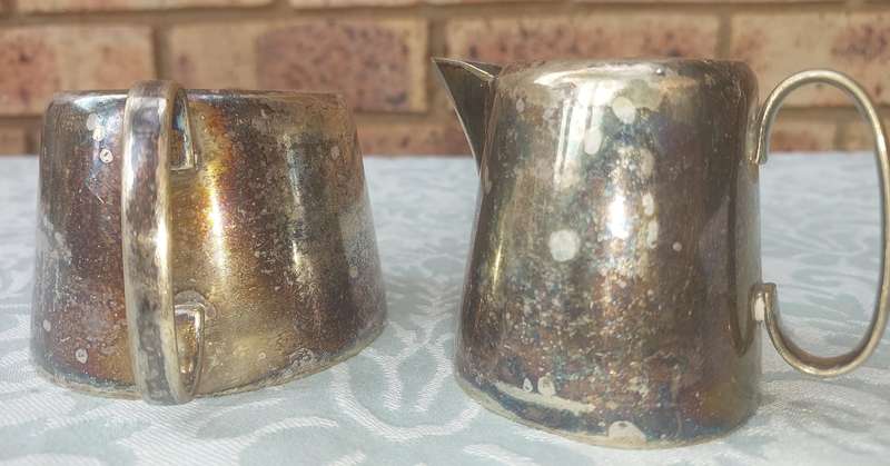 A VINTAGE SET OF SILVER PLATED MILK JUG AND SUGAR BOWL SOLD AS IS