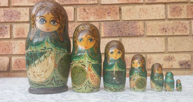 A VINTAGE SET OF RUSSIAN HAND PAINTED STACKING DOLLS SOLD AS IS