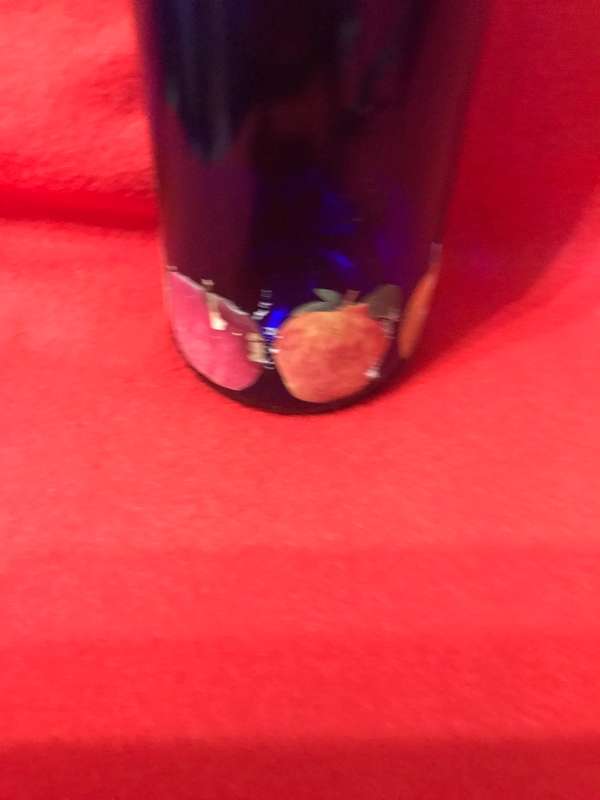 Cobalt bottle with printed apples and has a top