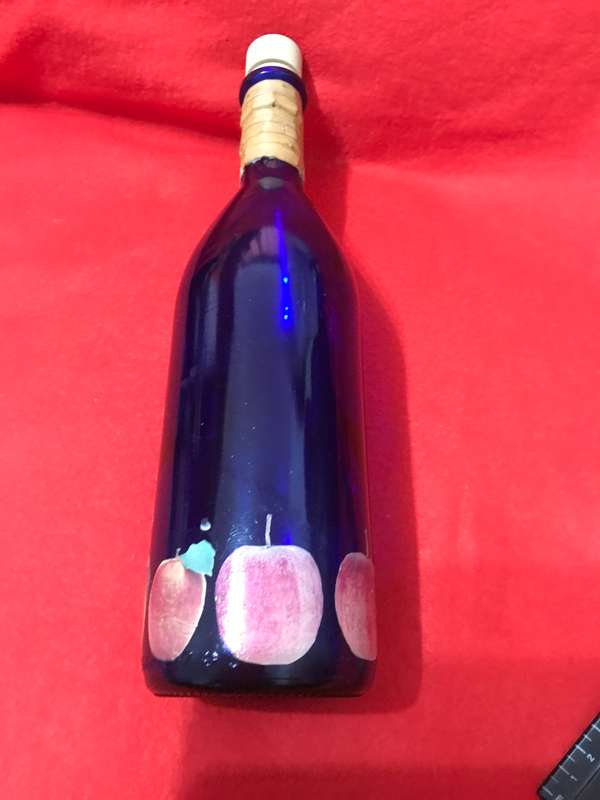 Cobalt bottle with printed apples and has a top