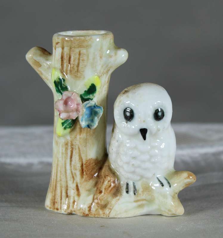 Miniature porcelain owl on a tree trunk