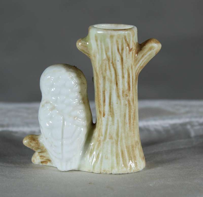 Miniature porcelain owl on a tree trunk