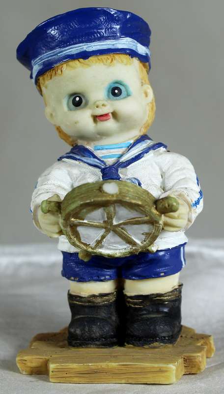 Boy sailor figure holding a ships wheel