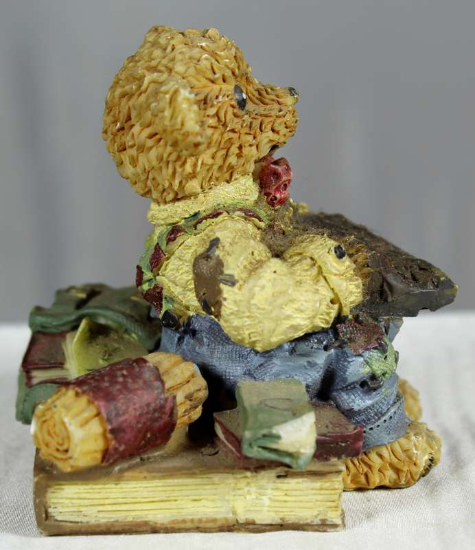 Little boy bear sitting between books