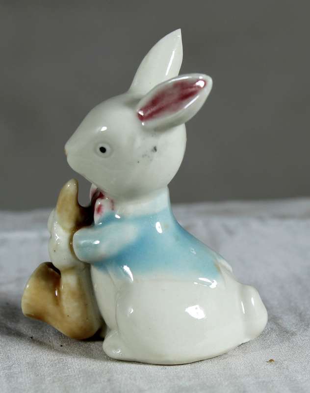 Miniature glazed ceramic bunny eating a carrot