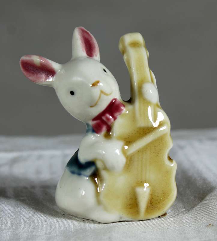 Miniature glazed ceramic bunny playing a bass