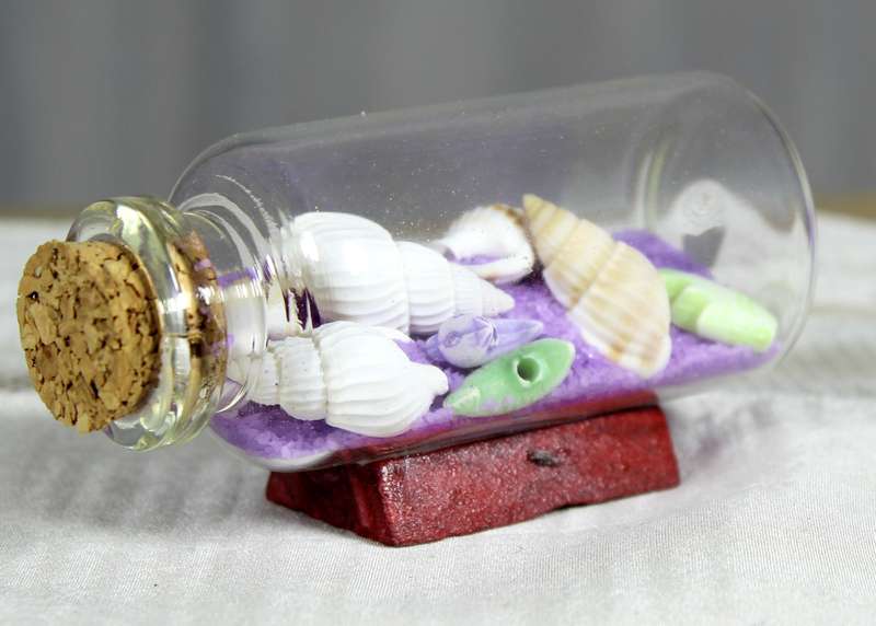 Miniature shells and purple sand in bottle