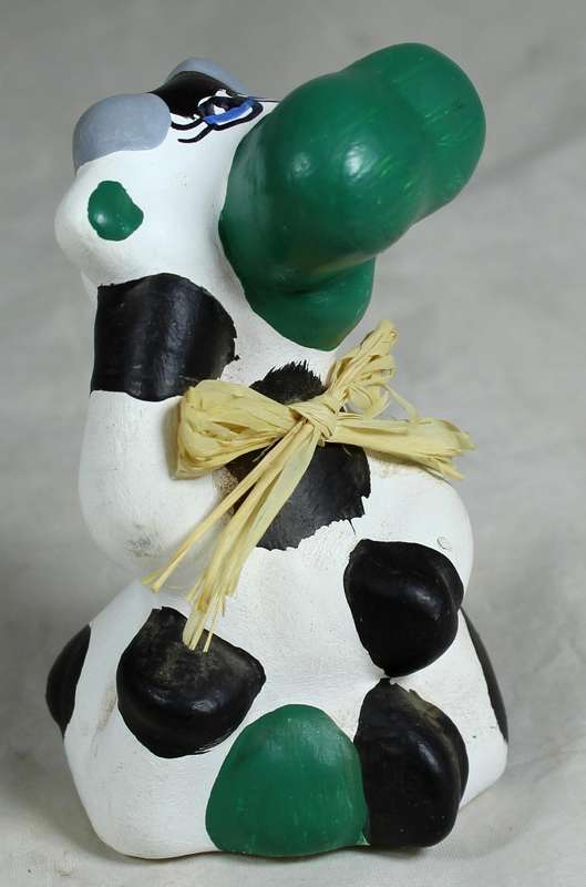 Ceramic cow seated with green nose
