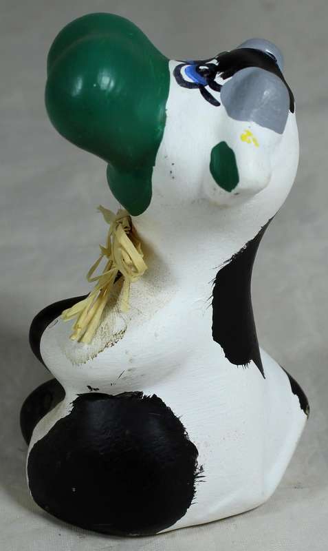 Ceramic cow seated with green nose