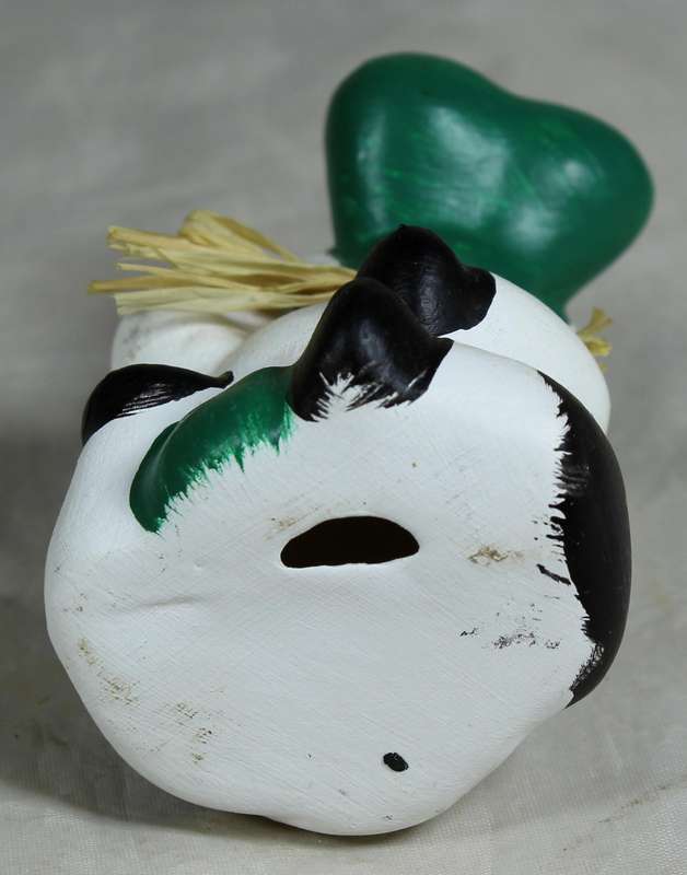 Ceramic cow seated with green nose