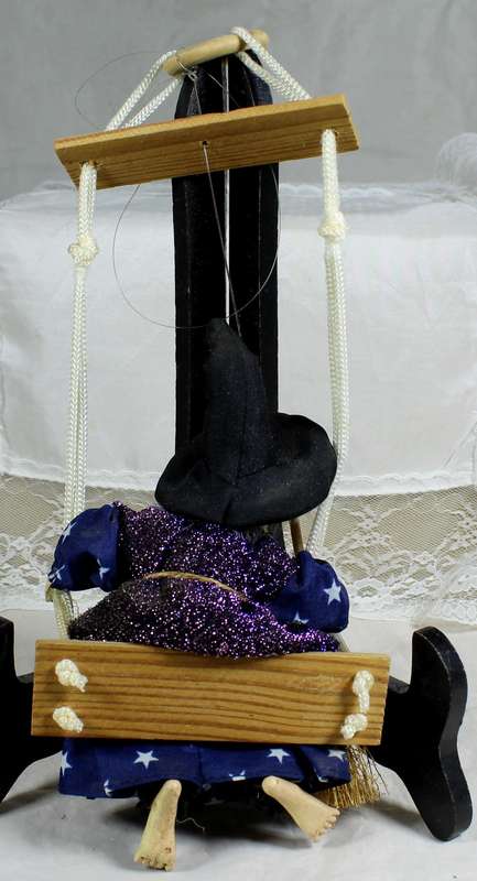 Witch with a broom on a swing