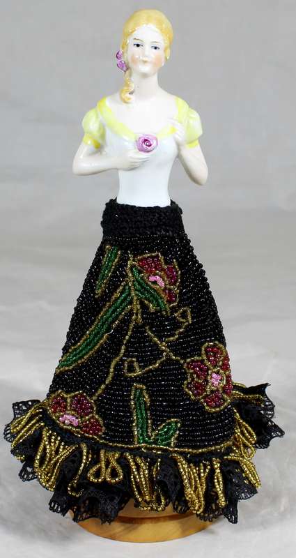 Half doll with beaded black dress on stand