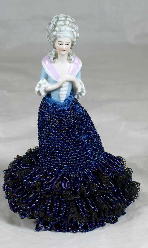 Half doll with beaded blue dress on stand