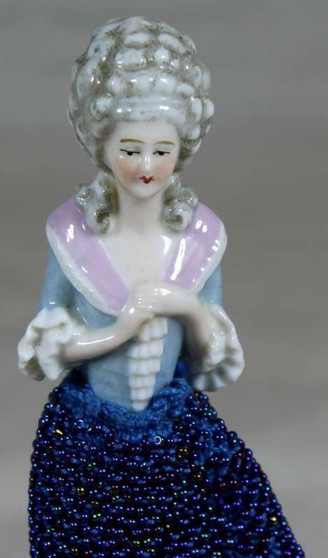 Half doll with beaded blue dress on stand
