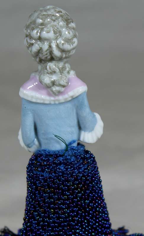 Half doll with beaded blue dress on stand