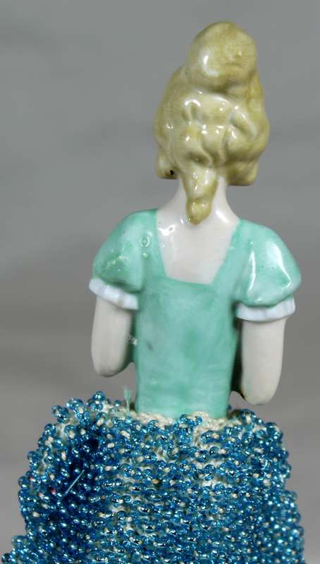 Half doll with beaded sea blue dress on stand