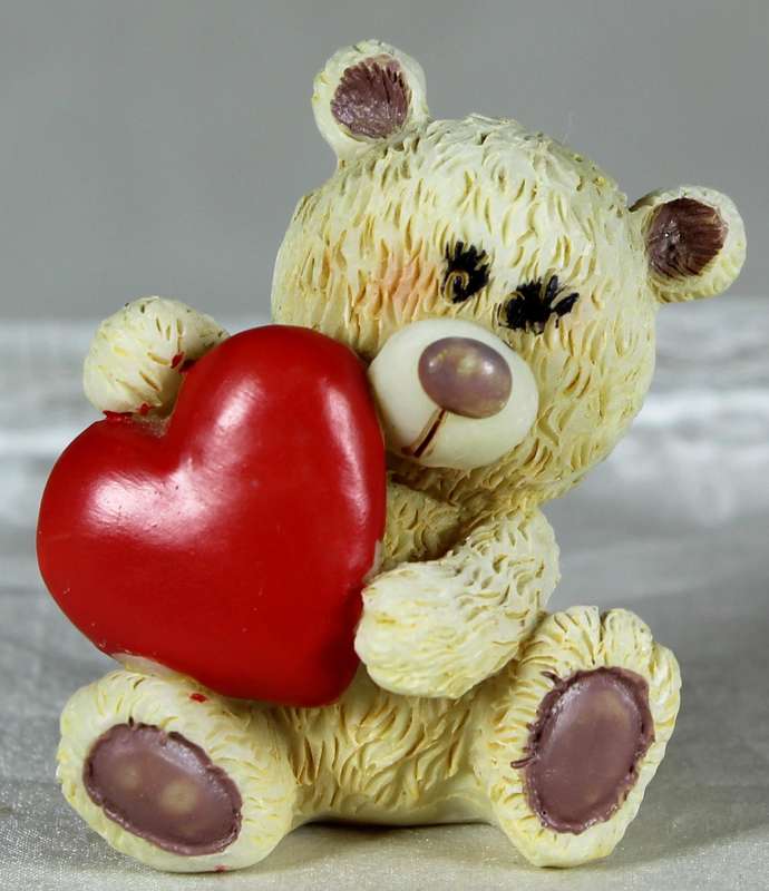 Miniature teddy bear holding a large heart