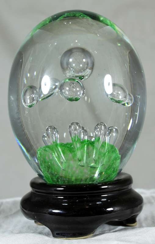 Glass paperweight with bubbles on green base on stand