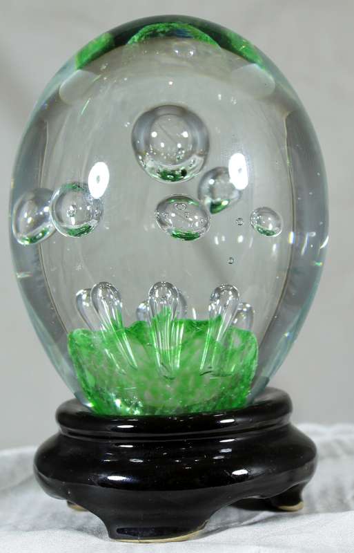 Glass paperweight with bubbles on green base on stand