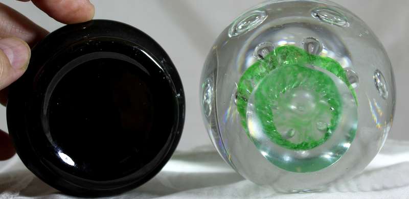 Glass paperweight with bubbles on green base on stand