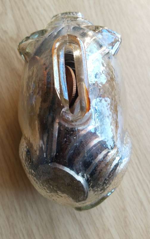 Glass piggy bank sealed full of mystery coins. Top chipped.