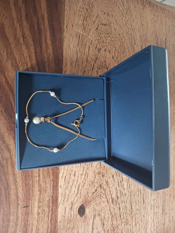 A 22 carat gold plated necklace with pearl and simulated diamond pendant,plus a bracelet.