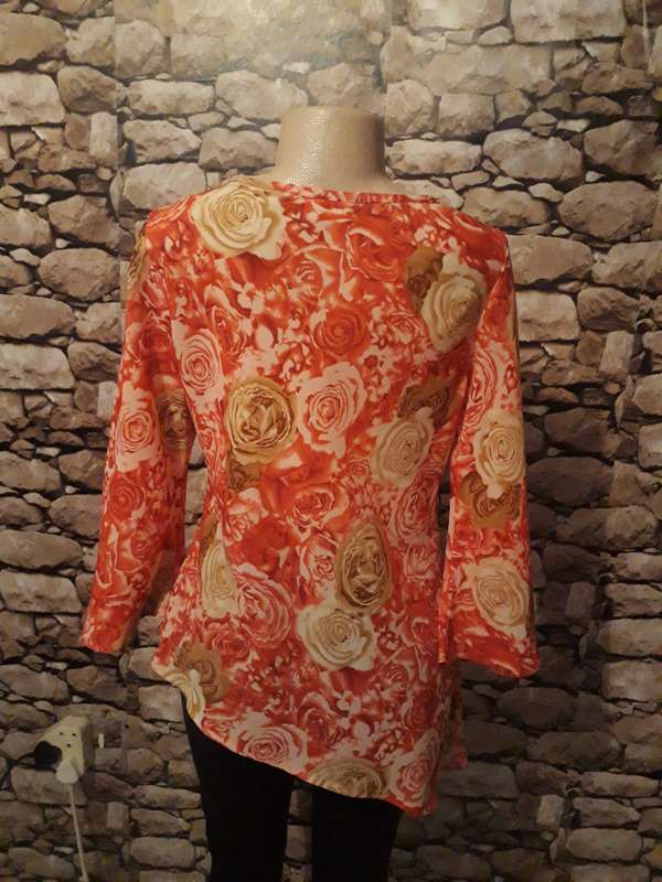 High/low throw over 100% polyester top with crimson, beige and brown flowers.
