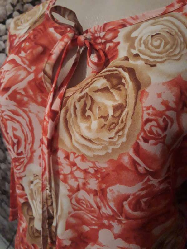 High/low throw over 100% polyester top with crimson, beige and brown flowers.