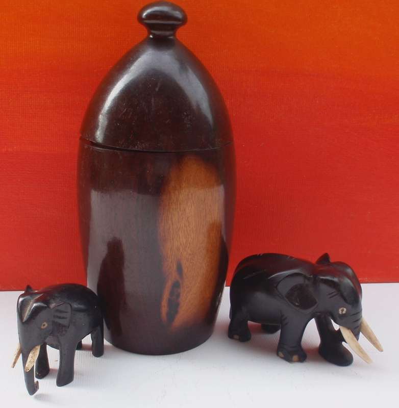 Beautifully carved wooden urn and two elephants .