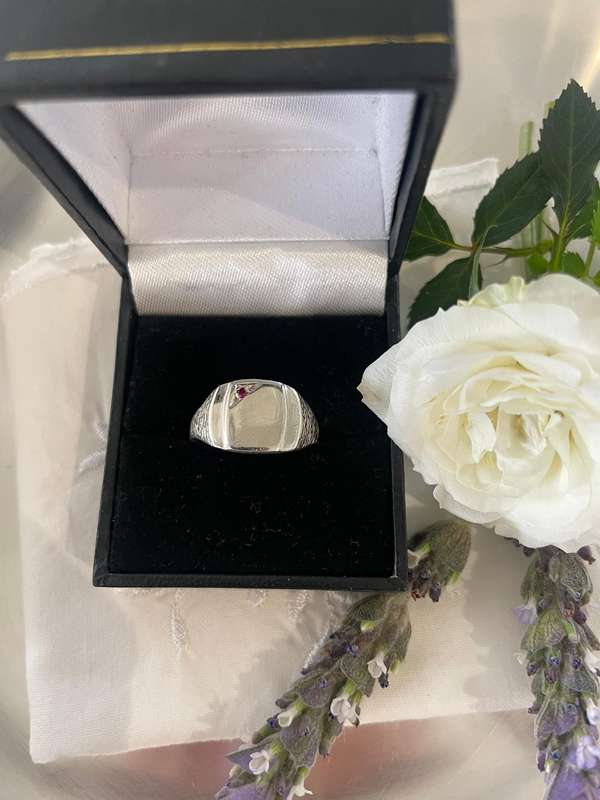 Sterling silver signet ring with a red gemstone, likely a ruby or garnet.