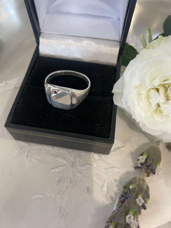 Sterling silver signet ring with a red gemstone, likely a ruby or garnet.