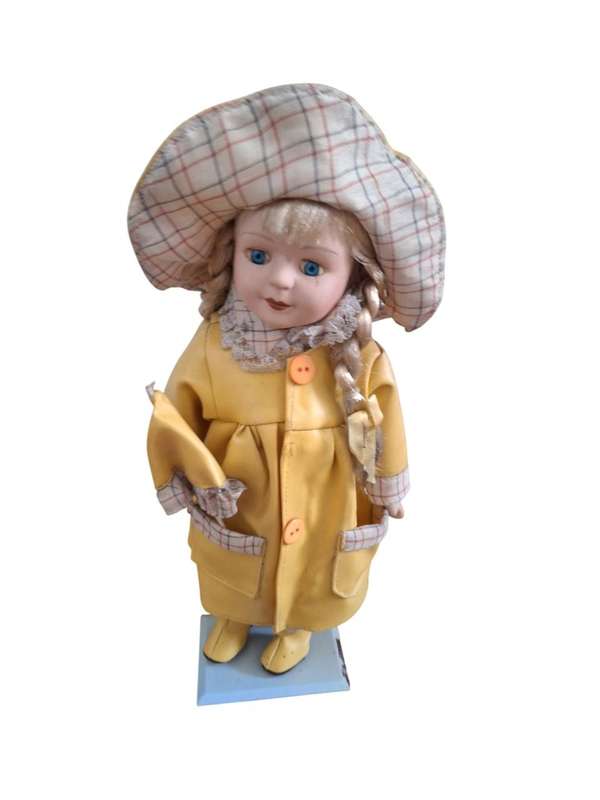 Vintage porcelain doll dressed for the rain with stand