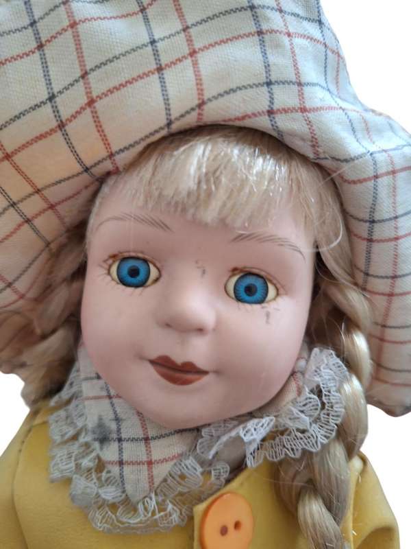 Vintage porcelain doll dressed for the rain with stand