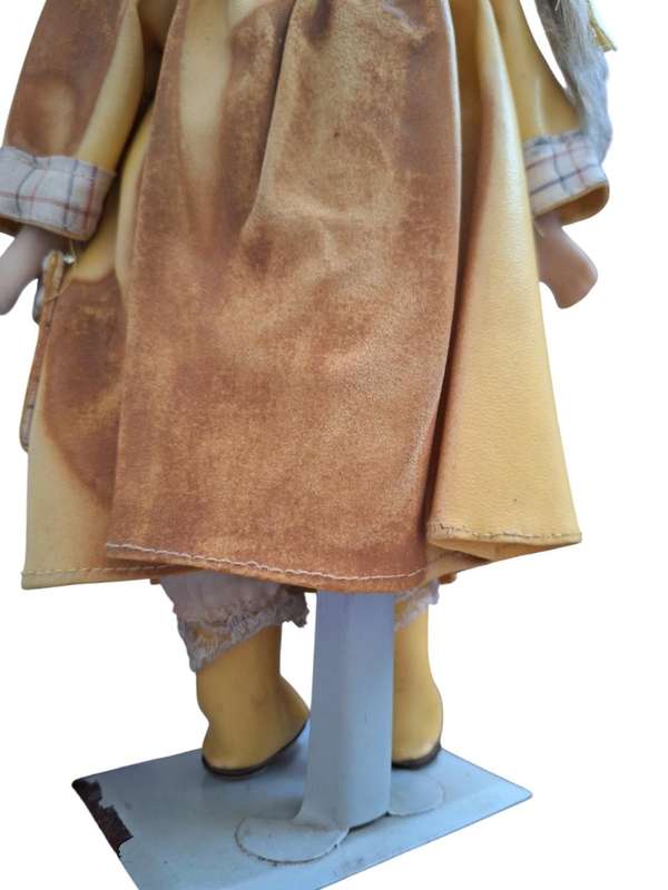 Vintage porcelain doll dressed for the rain with stand
