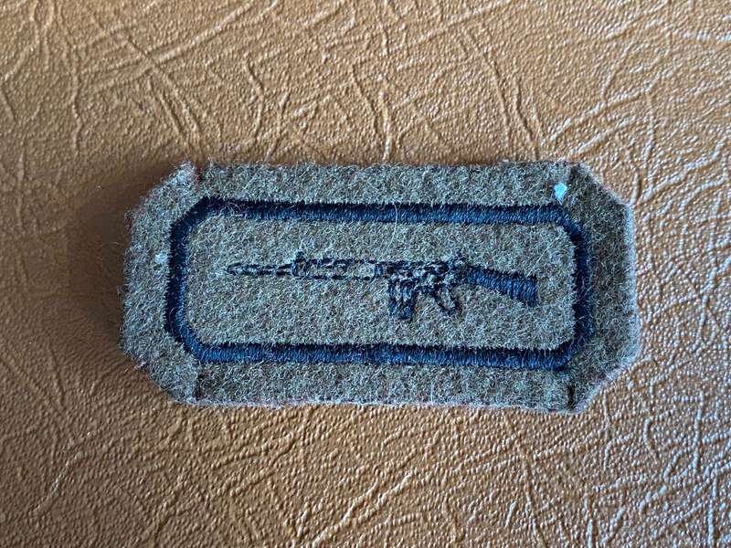 SADF 3RD TYPE MUSKETRY BADGE-RIFLE IN BLACK HAS DETAIL EMBROIDERED ON A BROWN FELT BACKING