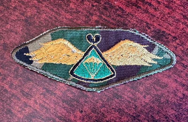 Lesotho defence force basic parachute wing. Gold thread wings with green centre. Embroidered on camo