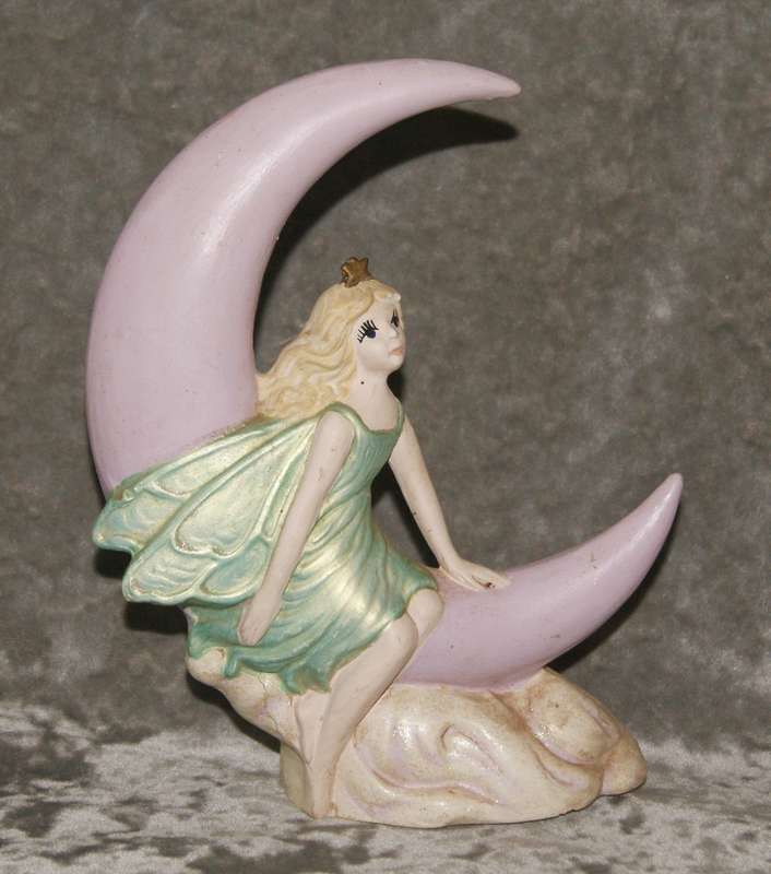 Ceramic fairy sitting on a moon statue