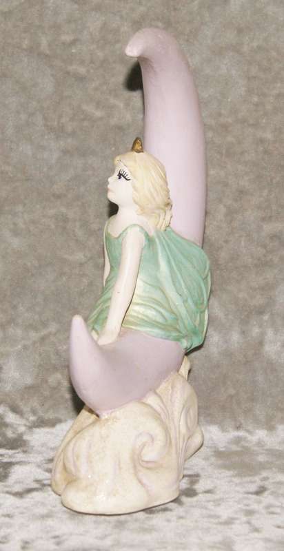 Ceramic fairy sitting on a moon statue