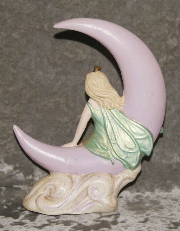 Ceramic fairy sitting on a moon statue