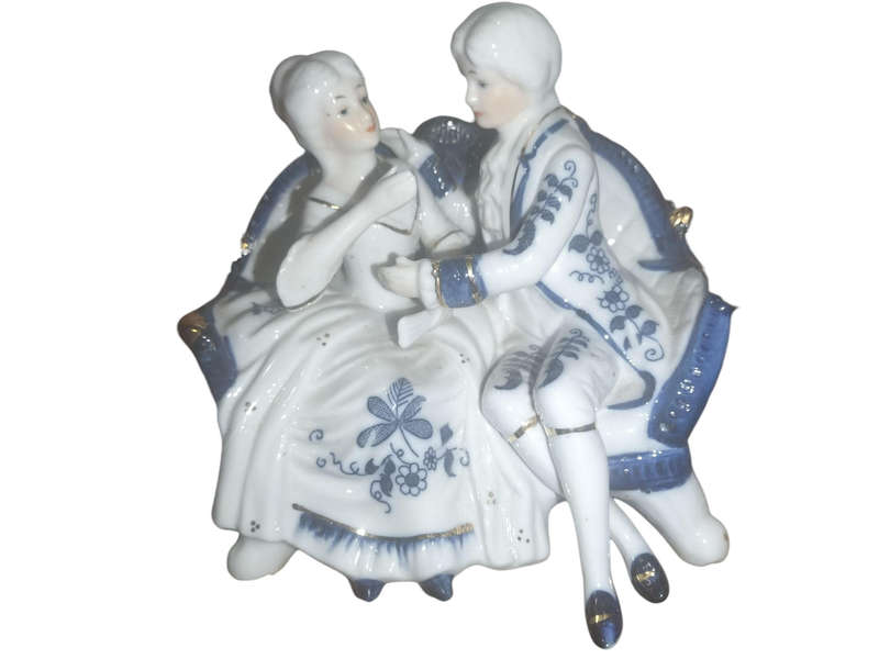 vintage collectable porcelain figurine of a couple sitting on a sofa.