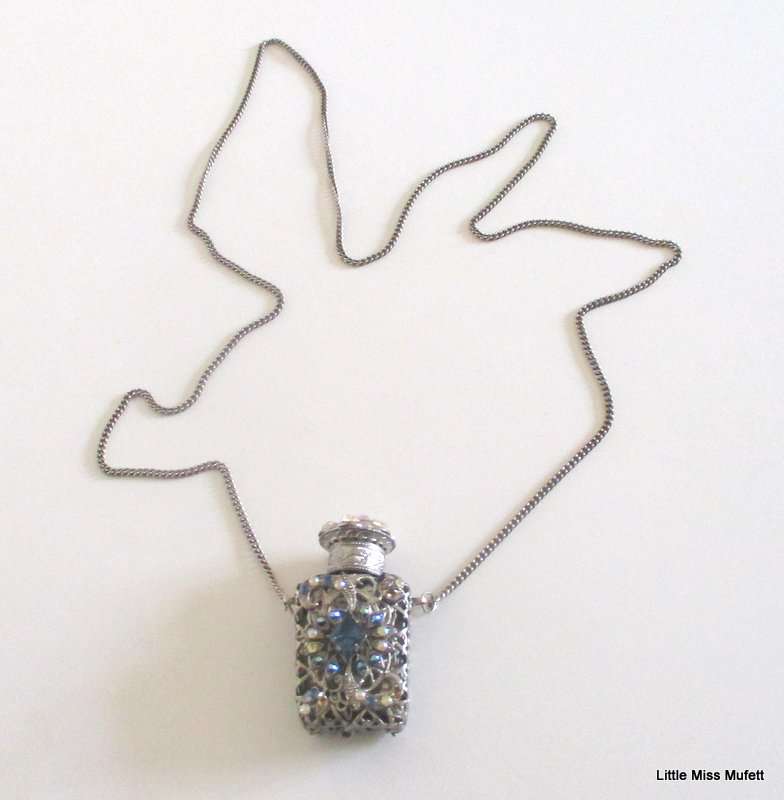 A silver tone Czech Perfume bottle on a long chain