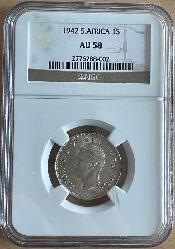 1942 SA shilling NGC AU 58. Rare multiple errors. A long cracked die and a cud flaw (extra metal)