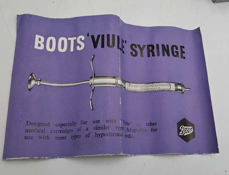 Boots viule syringe in a metal case with two glass containers with needles inside.