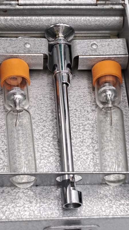 Boots viule syringe in a metal case with two glass containers with needles inside.