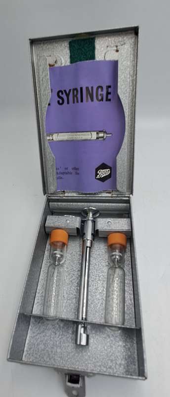 Boots viule syringe in a metal case with two glass containers with needles inside.
