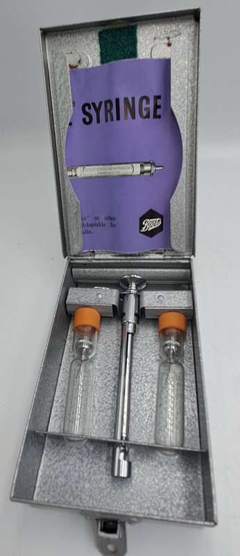 Boots viule syringe in a metal case with two glass containers with needles inside.