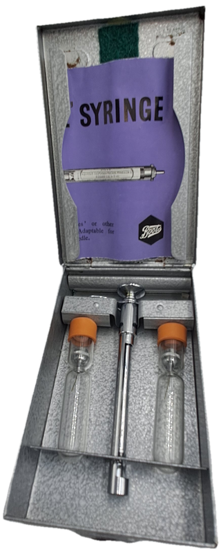 Boots viule syringe in a metal case with two glass containers with needles inside.