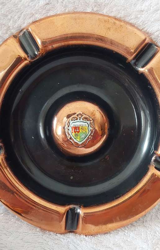 A lot of two vintage red copper ashtrays with small porcelain SA coat of arms in centre