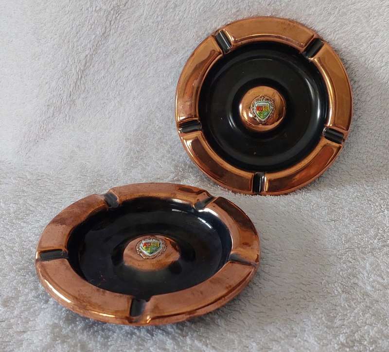 A lot of two vintage red copper ashtrays with small porcelain SA coat of arms in centre